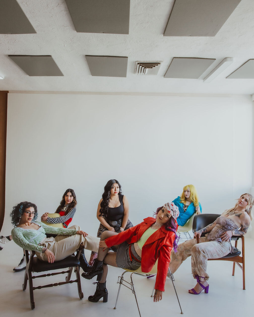 Lavish Hair Lounge stylists lounging on chairs in a bright white room with a high ceiling